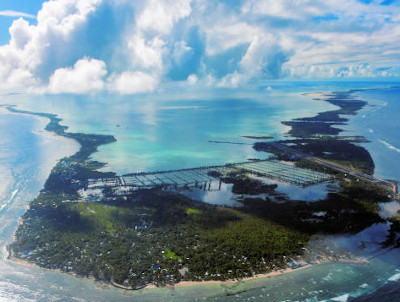 Tarawa Atoll, Kiribati: aerial view from the eastern end (Bikenibeu, Bonriki) with the south on the left and north on the right, surrounded by the coral reef barrier - Tarawa is an atoll in the Gilbert Islands, the most populous archipelago in Kiribati. Tarawa is the former capital of the British colony of Gilbert and Ellice Islands. Part of the atoll is occupied by the country's capital, South Tarawa. Tarawa has a largely Micronesian population. During World War II, Tarawa was occupied by the Japanese Empire and in 1943 it was the site of the bloody Battle of Tarawa.